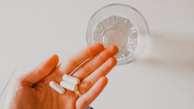 Supplements in hand with glass of water