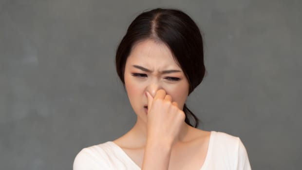 woman holding her nose to avoid disgusting smell